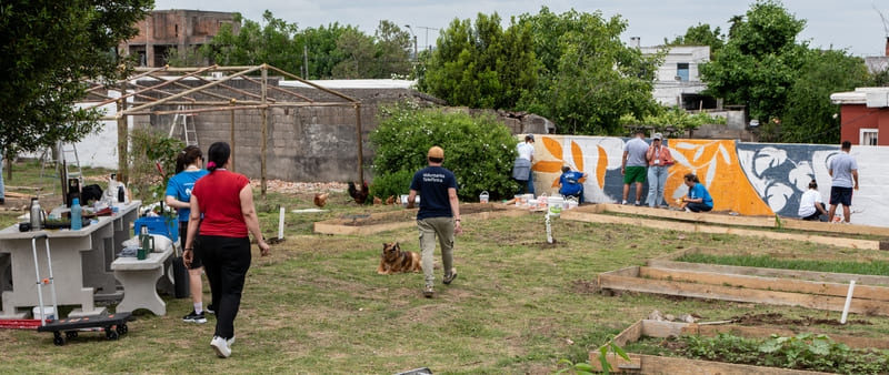 Patio grande con jóvenes pintando mural e invernáculo